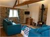 Lounge area with vaulted ceiling and beams, original exposed Brick & Flint wall.  Central wood burner and window outlook across the meadow.