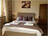 Master Bedroom with Kingsize beds.  Vaulted ceiling with beams. Original exposed Brick & Flint wall.  Window looking out across to the countryside.