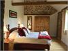 Large Master Bedroom with original exposed Brick & Flint Walls with vaulted ceiling and beams.  Window looking out over meadow.