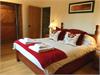 Large Master Bedroom with original exposed Brick & Flint walls with vaulted ceiling and beams. Window over looking the meadow